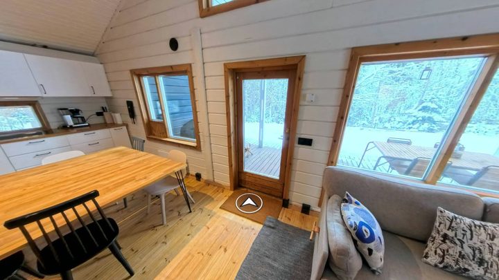 Inside the living room of the demo tour: a chevron lying flat on the wooden floor, pointing through the doorway to the entrance
